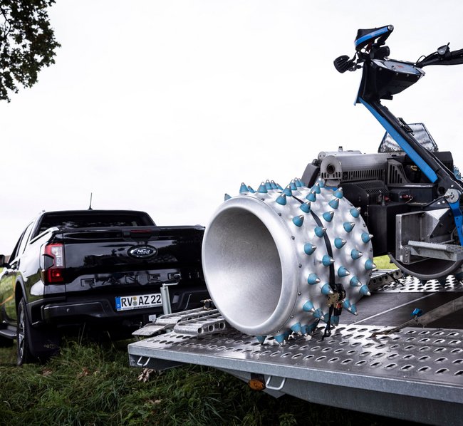 Ein Pickup steht auf einer Wiese mit Anhänger, der einen Brielmaier Einachser geladen hat. Damit werden Maschinen abgeholt und geliefert.