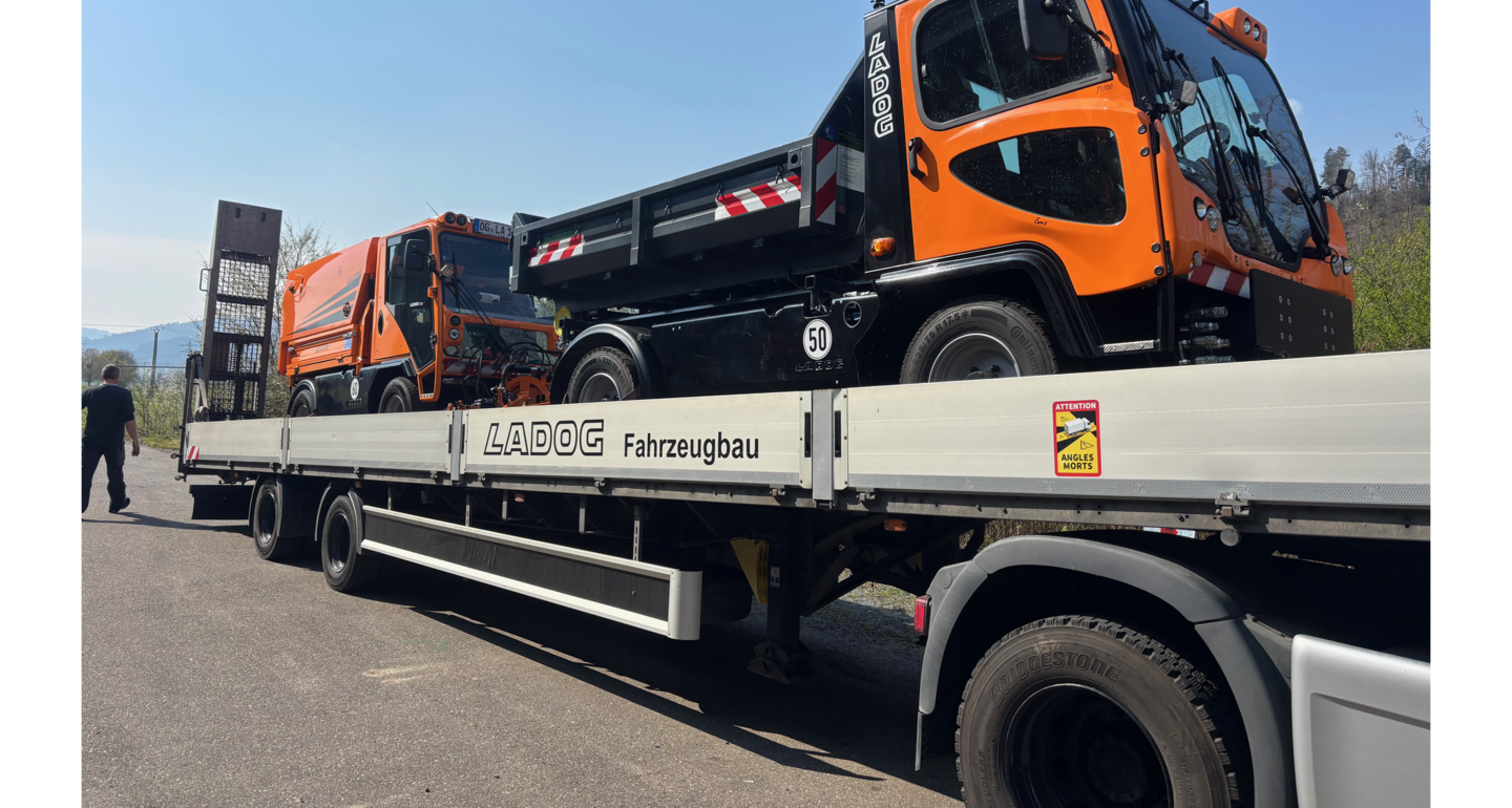 Zwei Kommunalfahrzeuge auf einem großen Sattelschlepper.