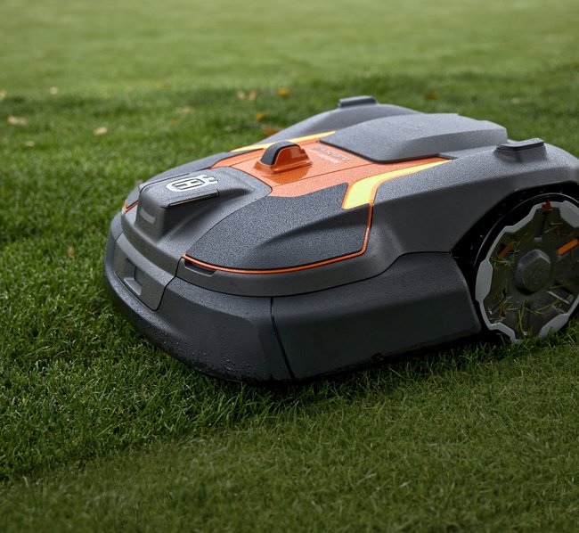 Ein autonomer Mähroboter fährt über einen grünen Rasen und schneidet das Gras.