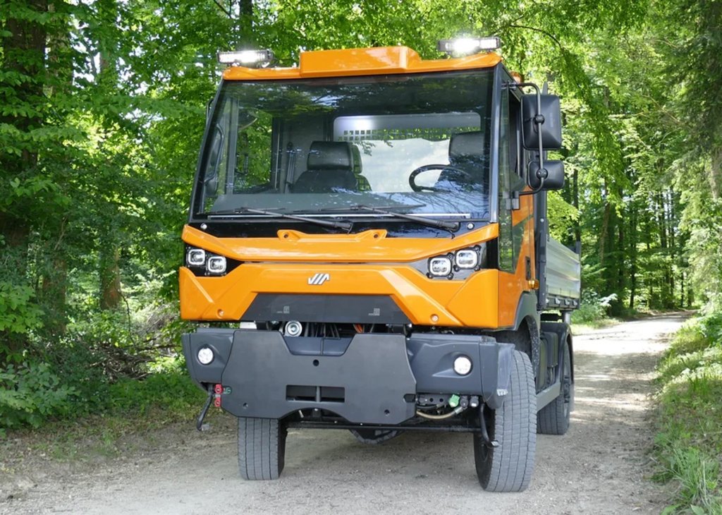 Auf einem Waldweg fährt ein orangefarbener Mehrzweck-Transporter der Firma Aebi.