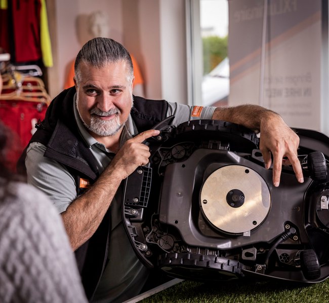 Beratungsgespräch von einem Mitarbeiter der Firma Bentele mit einem Smarten Roboter, der seitlich gedreht liegt, so dass mann den Roboter von unten sieht. 